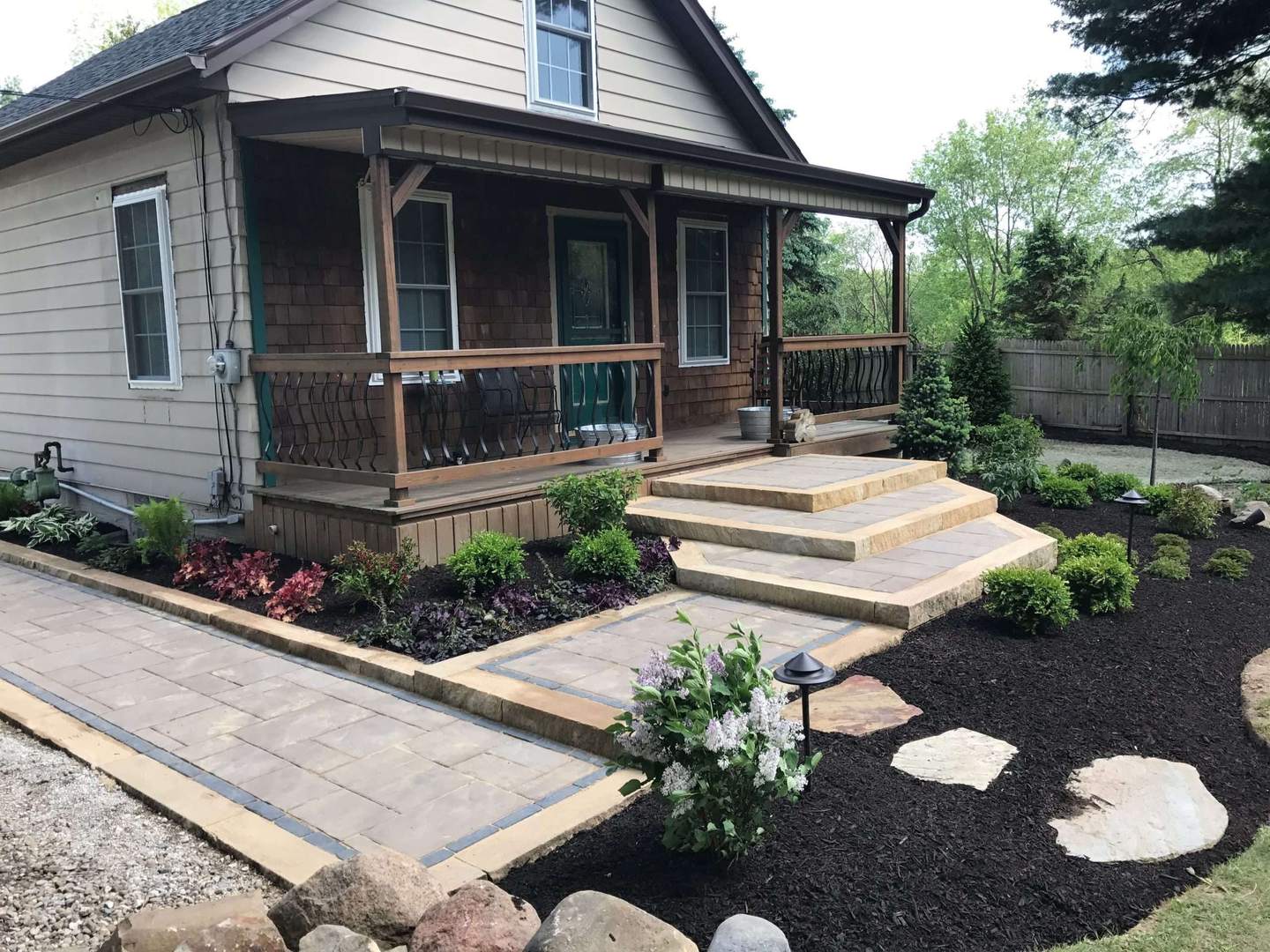 Large paver patio surrounded by garden beds